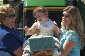 Two women holding up a chils with disabilities